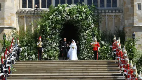 PA Prince Harry and Meghan Markle leave St George's Chapel though a gateway of flowers.