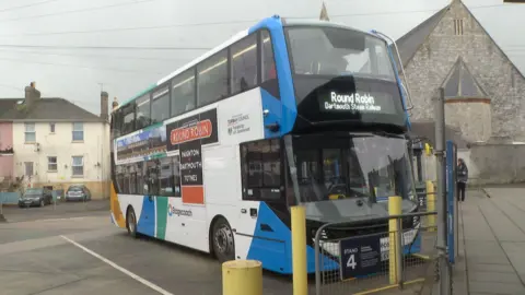 A new Stagecoach electric bus waiting at the stand at Paignton Bus station. The bus has a sign reading Round Robin on the side.