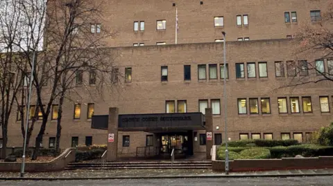 A picture of the front of Southwark Crown Court. It is a large brick building with many windows and an entrance at the front.