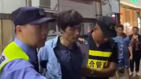 Reuters Police officers detain a man following a knife attack at a supermarket in Songjiang, Shanghai, China, in this screengrab obtained from a social media video released on October 1, 2024.