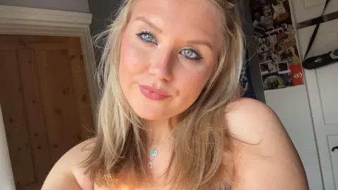 Family handout A selfie of a blonde girl with greenish, blue eyes in a bedroom