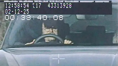 West Mercia Police Hammond is captured in a police image driving his Porche. He has glasses on and his sun visor down as he drives.