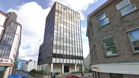 Google A picture of Union House in its current form, a rectangular brown office block with eight floors. The blue sky is visible in the background. 