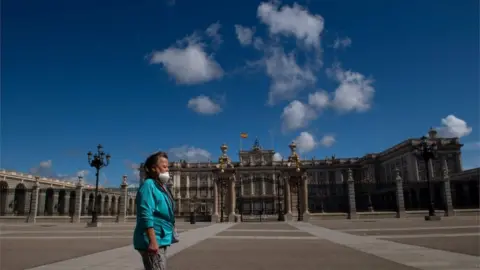 AFP A woman walks in front of the Royal Palace in Madrid on May 10, 2020 during the hours allowed by the government to exercise
