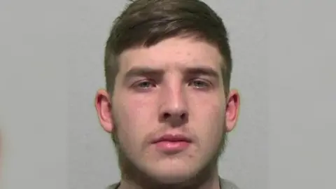 National Crime Agency Mugshot of Marshall Scurfield, who has a beard and brown hair.