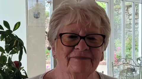 Dawn Tinley A picture of a lady with grey hair and black glasses. She is smiling at the camera.