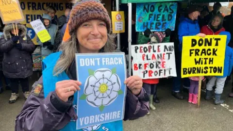 Christine McKay stood in front of a group of protesters while holding up a poster that says: "Don't frack Yorkshire."