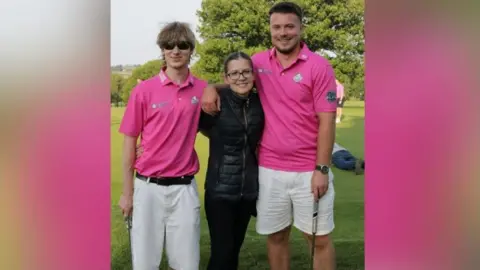 Harry and Freddie Philp Freddie and Harry Philp pictured in pink and white golfing gear, holding golfing sticks on a field and posing with Sarah, their mother, who is wearing black