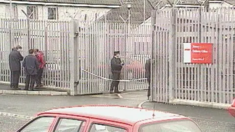VT Freeze Frame Police stand outside the scene of the murder, a fenced off Royal Mail sorting office in Newry.