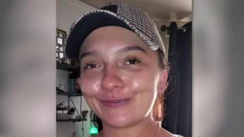 Social media  Woman smiling with a patterned baseball cap on and hair tied back 