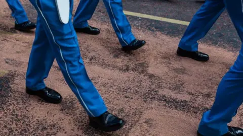 Getty Images  Legs of man in blue trousers and black shoes walking on the road 