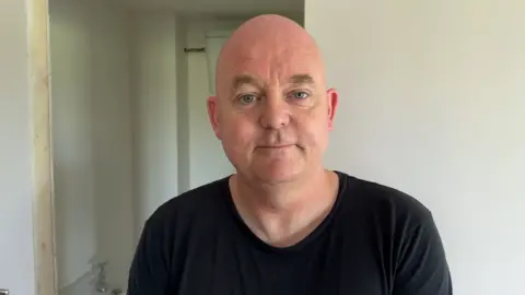 Mike looking at the camera wearing a black t-shirt.