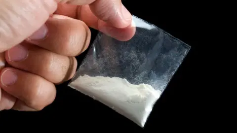 Getty Images Generic image showing a close up of a hand holding a small clear bag with white powder inside