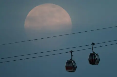 Reuters The supermoon rises in the sky above the Emirates Air Line cable car in London