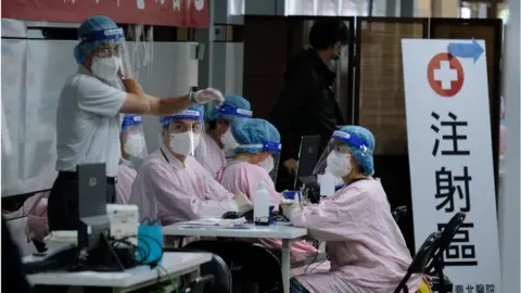 Getty Images Staff in PPE waiting for people to get their inoculation at a popup walk-in COVID-19 vaccination center in Taipei Main station in Taipei, Taiwan, December 10, 2021.