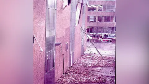 HMSO An archive image of the building at GF with lots of debris on the floor, and lots of holes in the building.