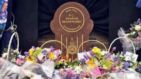 Police Memorial Trust Flowers and tributes lay in front of a memorial stone, which reads: "Here fell PC Sharon Beshenivsky".