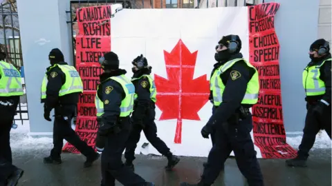 Getty Images A group of police officers walk past a Canadian flag near Parliament Hill