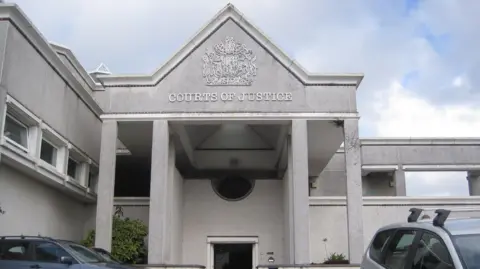 PA Media The exterior of the Courts of Justice building at Truro. It has four pillars holding a triangular structure. There are three cars parked near to the entrance. 