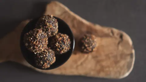 A bowl of home baked protein balls on a rustic chopping board