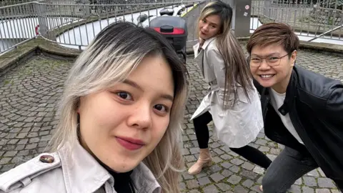 Rungtiwa Thangkanopast Rungtiwa dan Phanlavee berpose di latar belakang saat putri mereka berfoto selfie bersama mereka 