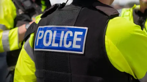 A generic picture of a police officer, who has police stamped on a stab vest and a high-visibility jacket underneath it.