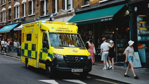 An NHS ambulance is parked on Charing Cross Road, London.