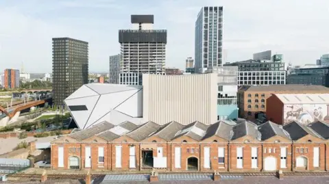 Riba The white geometric Aviva Studis can be seen between warehouses, at the front of the picture, and the Manchester skyline at the back.