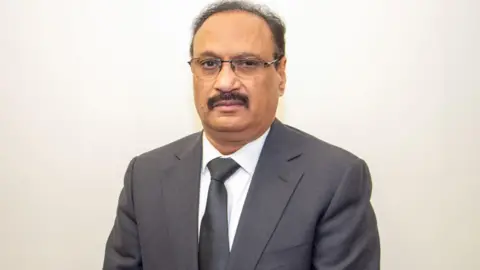 Kuldeep Shekhawat  Man in grey blazer and tie 