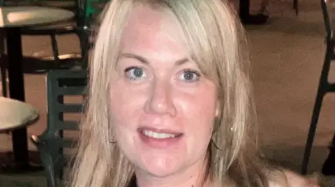 Heather Steele A close up picture of a woman with blonde hair. Tables and chair can be seen in the background.