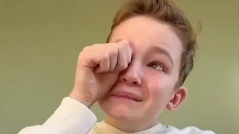 Boy rubs his eye as he makes tearful announcement in video