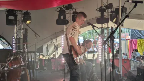 Supplied A young man playing guitar on stage at a music festival