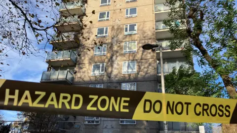 Hazard Zone tape in front of The Combe building.