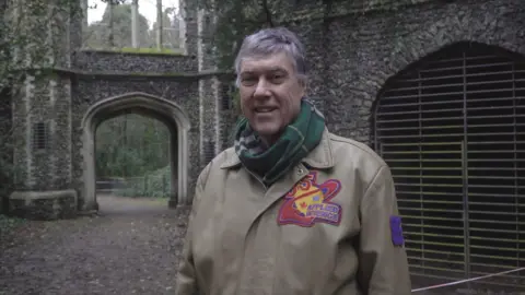 Local Democracy Reporting Service/Oliver Leader de Saxe A man in a taupe coat standing in front of a historic building.