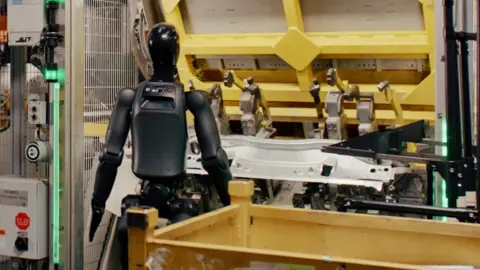 BMW The black Figure humanoid robot stands in front of a machine at a BMW car plant