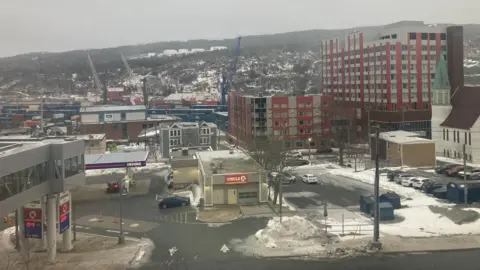 Jon Shipman Snow-covered buildings, including a petrol station and several apartment blocks. The urban views give way to a snow-capped tundra. 