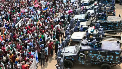 Getty Images People rally before security forces' vehicles at a mass demonstration near the presidential palace in Sudan's capital Khartoum