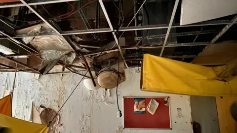 An abandoned pain clinic is painted with a caved in the wall