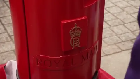 BBC A red post box with King Charles' cypher on it, and "Royal Mail" embossed below