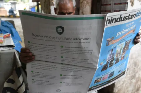 AFP An Indian newspaper vendor reads a newspaper with a full back page advertisement from WhatsApp intended to counter fake information in Delhi on July 10 2018.