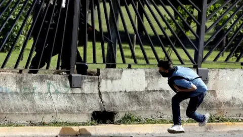 Reuters A member of the riot security forces points a gun through the fence of an air force base at David Jose Vallenilla, who was fatally injured during clashes at a rally against Venezuelan President Nicolas Mauro's government in Caracas, Venezuela, June 22, 2017.