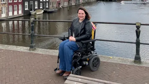 Sam Jennings Sam Jennings on a bridge in her powerchair during trip to Amsterdam.