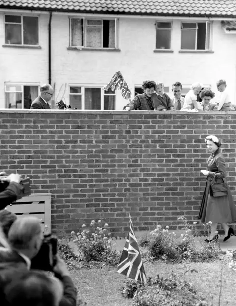 PA Media A Union Jack planted in the garden caught the Queen's attention, but she is the object of the neighbours' gaze. They watched as she arrived to visit the home of Mr and Mrs Eddie Hammond at Crawley New Town, Sussex after opening Gatwick Airport. 1958