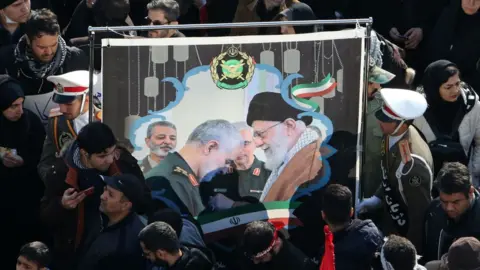 AFP Mourners hold up a picture of Iran's supreme leader and Qasem Soleimani