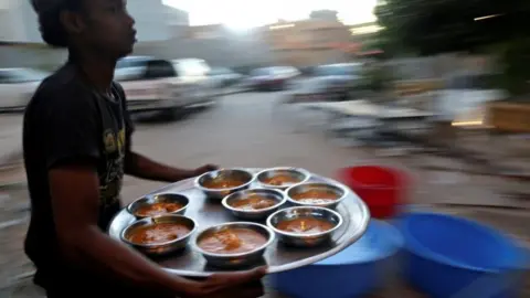 Reuters A man carries food to tables of Muslims eating their Iftar (breaking of fast) meal during Ramadan in Benghazi