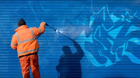 Getty Images Man removes graffiti in hi vis