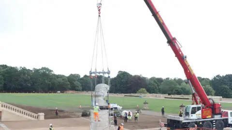 Crystal Palace Park Trust Two construction workers moving the bust onto a truck with multiple harnesses