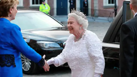 PA Media The Queen shaking hands as she arrives at the State Banquet in Dublin wearing the white dress adorned with shamrocks. 