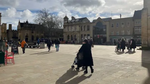 Shariqua Ahmed/BBC Peterborough's Cathedral Square, including buildings with historical architecture and members of the public walking around.