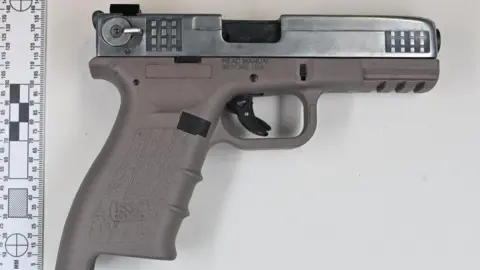 Metropolitan Police A converted pistol photographed on a flat surface next to a measurement scale.